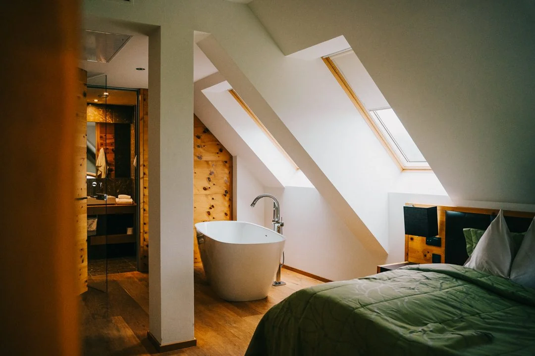 Dachgeschosszimmer mit freistehender Badewanne und Holzwand